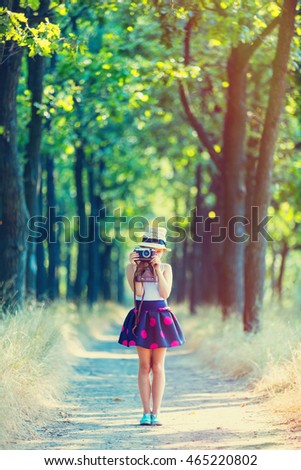 photo of the beautiful girl with camera on the countryside road