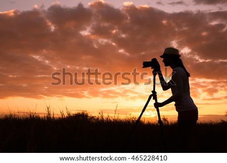 Female photographer capturing a beautiful sunset. 