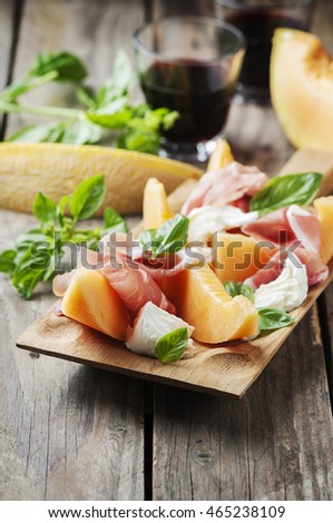 Antipasto with melon, mozzarella, ham and basil, selective focus