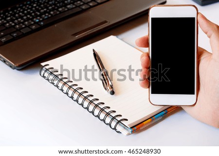 Close up of a men using smart phone with blank mobile and calculator, pen, notebook. Smart phone with blank screen with clipping path. Hand using a white smart phone on a desk at home, soft focus.