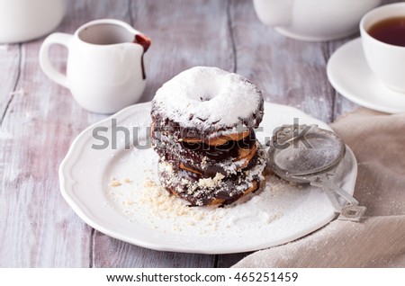 Fresh powdered sugar donuts, country style and tea for Breakfast on white wooden table