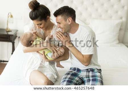Young couple on the bed with baby girl