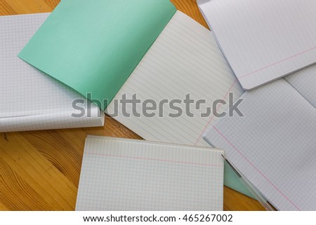 Open white lined exercise books on a light orange wooden study table atop close-up