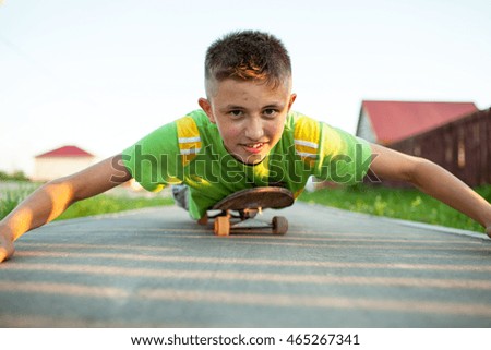 A teenager on a skateboard lying on his stomach