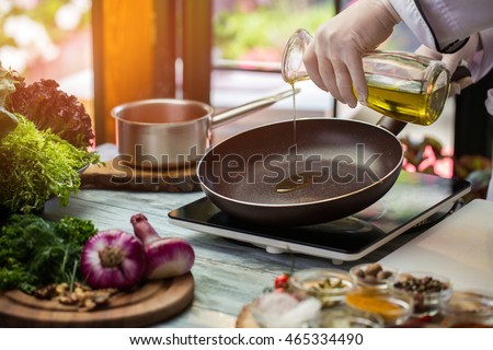 Jug pours liquid on pan. Green lettuce and purple onion. Frying pan is warming up. Need some olive oil. Royalty-Free Stock Photo #465334490