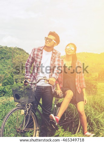 Couple of romantic lovers sitting on vintage bike in nature . Asian handsome man and beautiful girl is travel , hipster people, love, vintage tone and lifestyle concept