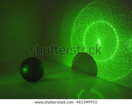 Dark ball with shadow on wall in green laser light