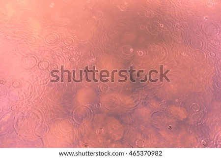 Blurred of water ripples and drops in pink color with stones at the bottom, for background
