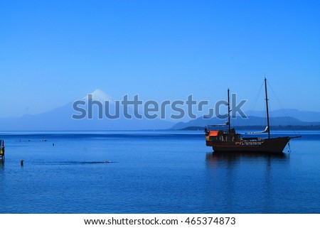 Old Sailing boat on a lake in front of a volcano