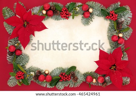 Poinsettia flowers with glitter forming an abstract background border with bauble decorations, holly, mistletoe and snow covered spruce fir leaf sprigs on old parchment paper over red.