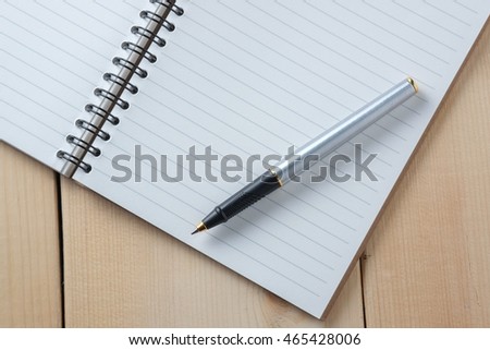 pen and book on wood background