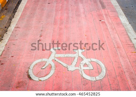 Old red bicycle lane with white bicycle sign on the ground around the park
