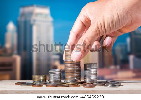 Male hand putting money coin like stack growing business on night city background. Finance and Money concept,Hope of investor concept
