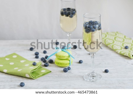 Glasses of champagne with blueberries and green macaroons