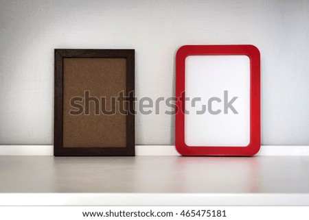 Two different style of picture frame on the white shelf; Vignette