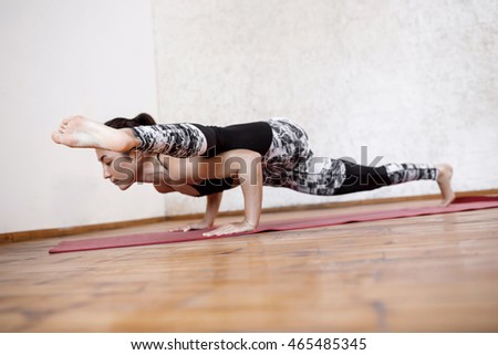 Young beautiful athletic girl practicing indoor yoga arm-balance. Eka Pada Koundiyanasana