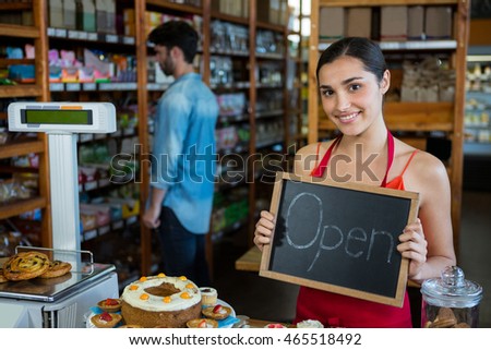 Portrait of woman holding open signboard in supermarket