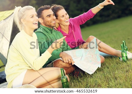 Picture of group of friends camping in forest and looking at map