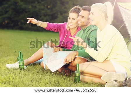 Picture showing group of friends camping in forest and looking at map
