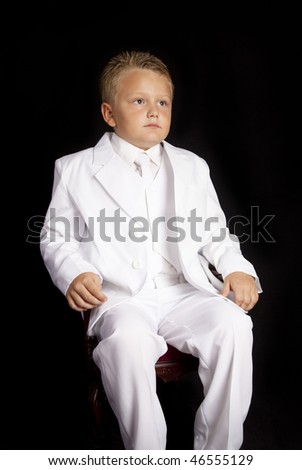 Handsome Young Boy in a White Suit sitting in chair