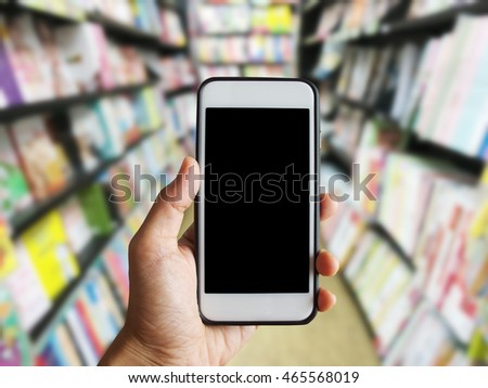 Holding a smart phone in the book store;bookshelf