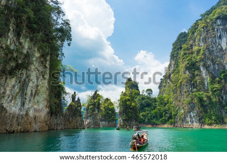 Tourist boat exploring epic limestone cliffs in huge lake in Khao Sok National Park, Chiew lan lake, Thailand. Royalty-Free Stock Photo #465572018