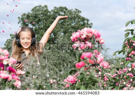 Teenager standing in roses and listen to music