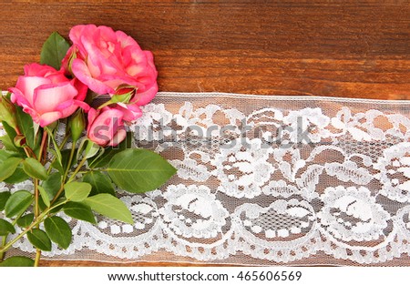 
beautiful flowers roses on a wooden background with lace