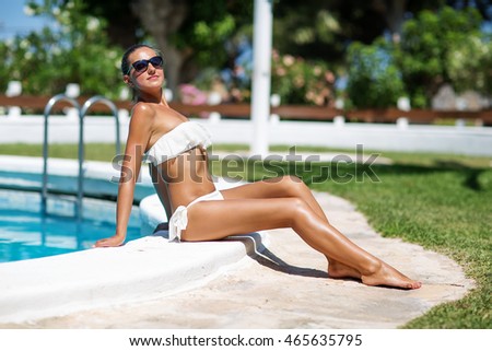 Young beautiful woman rests at the pool in summertime