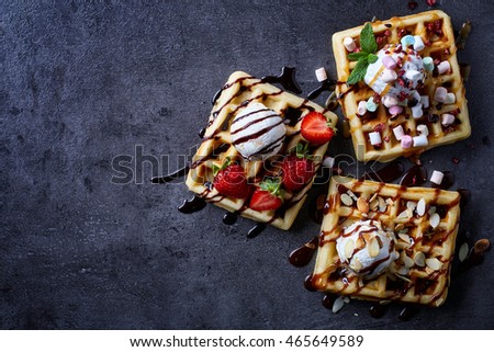 Three various belgian waffles on dark wooden background. From top view Royalty-Free Stock Photo #465649589