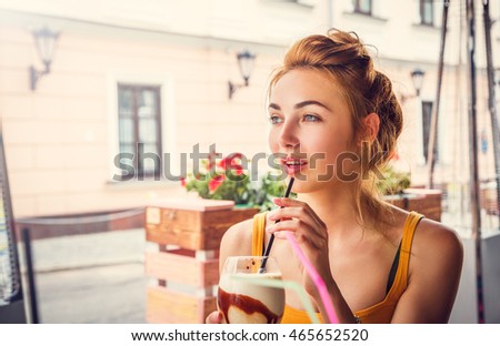 Young Fashion Woman Drinking Ice Coffee in a Cafe Outdoors in the City. Toned Instagram Styled Photo with Copy Space.