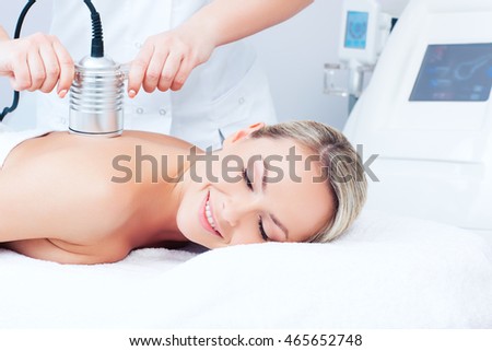 Hardware cosmetology. Picture of happy young woman with closed eyes getting cavitation procedure in a beauty parlour.