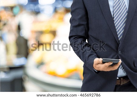 isolated business man with smart wristband and smartphone on shopping mall background
