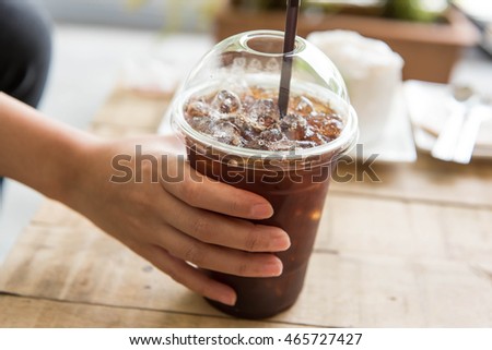 Woman hand holding Ice black coffee on wooden table,american Coffee,Americano