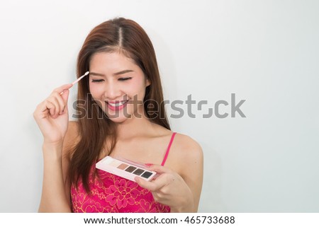 Young and attractive woman using mascara / photos of attractive young brunette woman on a white background .