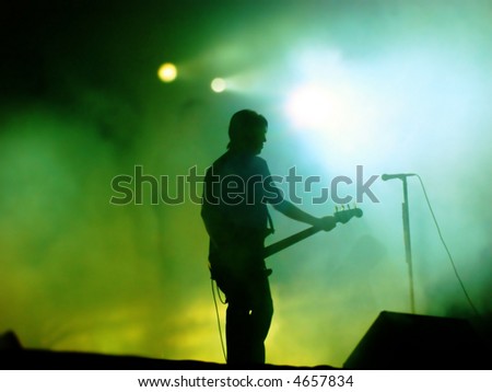 Guitarist On Stage (Silhouette Of Playing Guitarist On A Concert Stage)