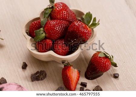 Fresh strawberries dipped in dark chocolate on wooden background