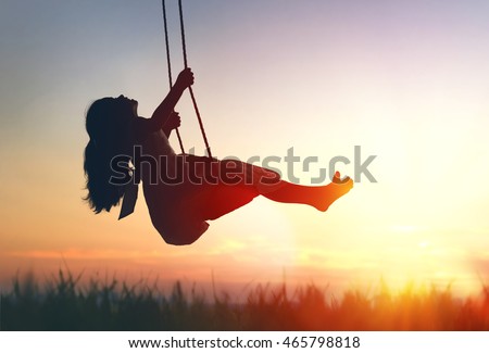 Happy laughing child girl on swing in sunset summer Royalty-Free Stock Photo #465798818