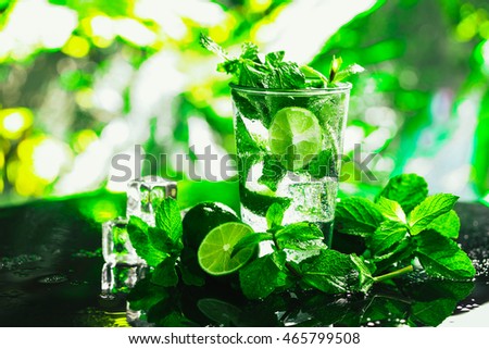 glass of mojito with lime and mint close-up ice cube on a dark background.