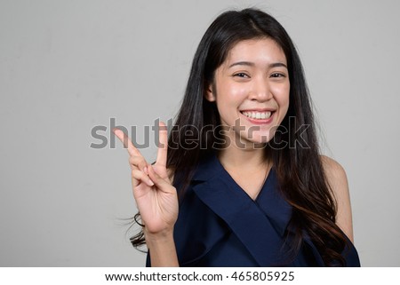 Portrait of young Asian woman smiling and making peace sign