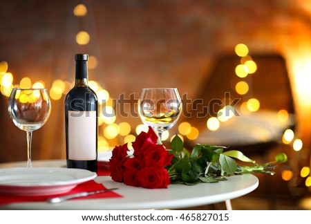 Romantic table setting with wine and beautiful roses on blurred background Royalty-Free Stock Photo #465827015