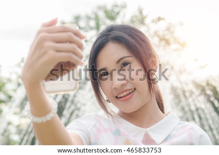 Beautiful asian girl taking her photo by smart phone outdoor
