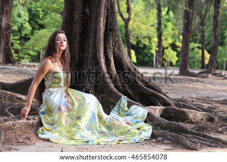 girl in long dress in the forest, young woman in full-length dress sitting near the tree's root,aphrodite in forest