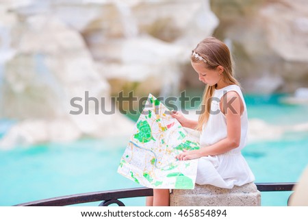 Adorable little girl looking at touristic map near Trevi Fountain, Rome, Italy. Happy toodler kid enjoy italian vacation holiday in Europe.