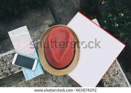 Travel, vacation concept. Phone, pizza box or empty blank, map and hat on natural outdoor street background. Top view with copy space for text.