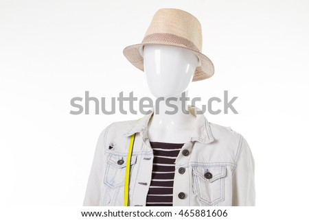 Female mannequin in beige hat. White denim jacket. Showcase of outlet store. Cheapest prices for clothing.