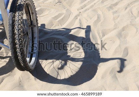 shadow of the wheel of the wheelchair on the sand of the beach