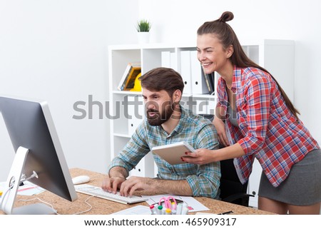 Man and woman looking at computer screen smiling. Concept of good time during coffee break