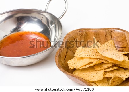 Tortilla Chips or nachos in wooden bowl with silver bowl of dipping sauce.