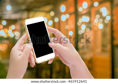 Hand holding mobile phone with blur night light of downtown background